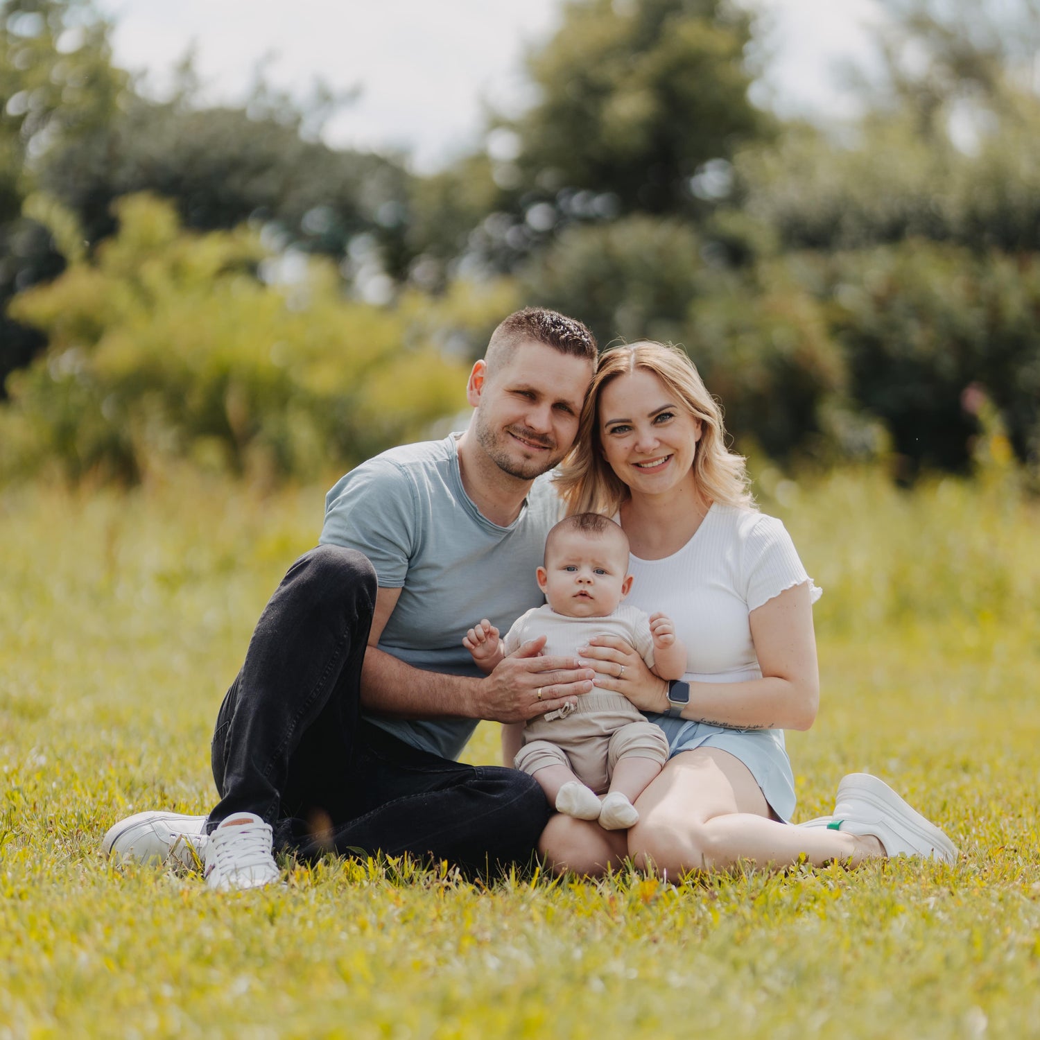Familie mit Vater, Mutter und einem kleinen Baby. Sitzen auf der Wiese