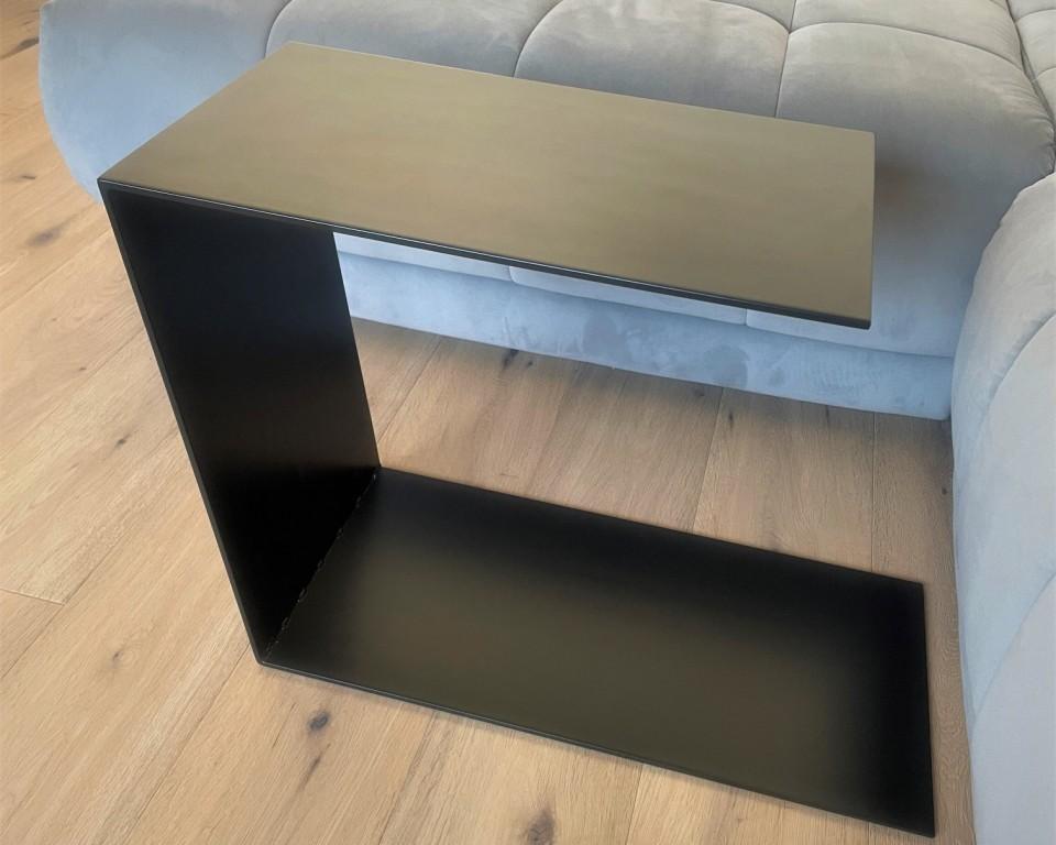 Couchtisch aus Metall, Farbe Scwharz. In Trapezform und U-Form der über ein Sofa geschoben wurde.