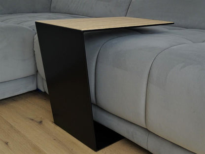 Couchtisch aus Metall, Farbe Scwharz und auf der Oberseite ist ein Eiche Furnier drauf geklebt. In Trapezform und U-Form der über ein Sofa geschoben ist. 